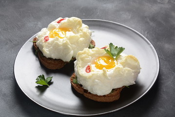 Delicate baked egg. Orsini eggs in the cloud. French breakfast.Cloud egg on toast 