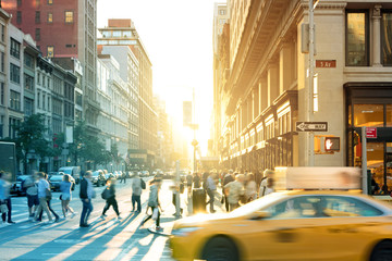 New York City yellow taxi cab speeds past the crowds of people at the intersection of 23rd Street...