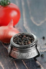 Tomatoes, onions, black pepper in silver dishes on a wooden background. Spices for cooking.