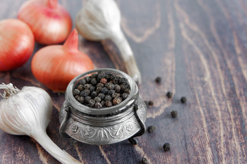 Onions, garlic, black pepper on the kitchen wooden table. Spices for cooking.