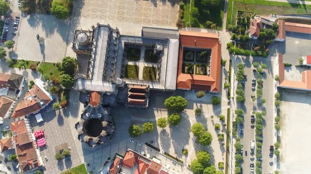 Aerial view centre of small portuguese town. Drone flying above ancient abbey upside view ruins, park with trees and towers in sun light. Portugal, Batalha