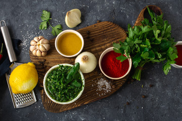 Ingredients for cooking Argentinian green Chimichurri or Chimmichurri salsa or sauce made of parsley, chili pepper, olive oil, garlic and vinegar