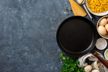 Ingredients for cooking healthy breakfast eggs with empty cooking pan and mushrooms, corn, eggs, spinach and cheese on dark stone background with copy space top view