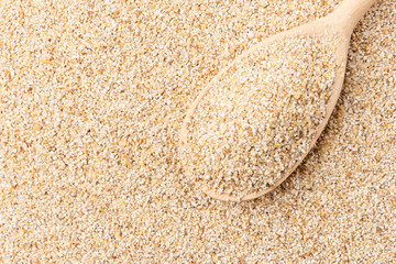 Fine-ground pearl barley background with wooden spoon.