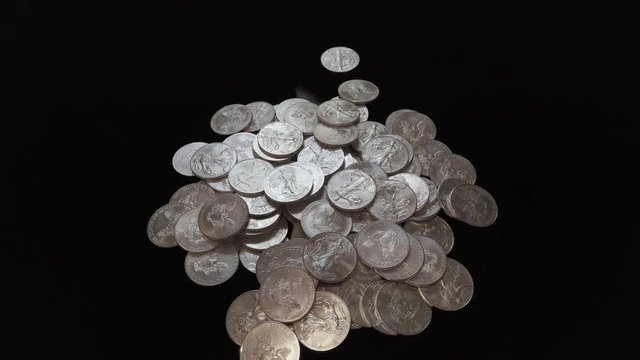 American Silver Eagle silver coins falling into a pile.