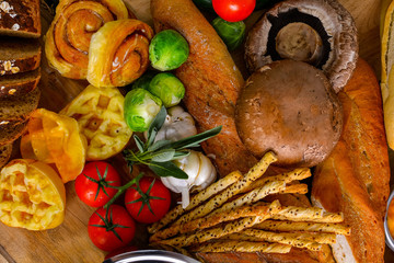 Warm bread from the stove And fresh vegetables arranged together,Sourdough ,cinnamao roll,waffle,garlic,and tomato,garlic,Brussels Sprouts,bread stick,portable mushroom top view