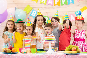 Group of preschool children having fun celebrating birthday party. Kids showing thumbs up sign or symbol