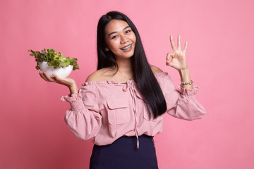 Healthy Asian woman show OK with salad.