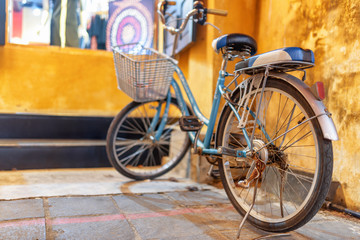 Fototapeta na wymiar Blue vintage style bicycle parked at yellow wall, Hoi An
