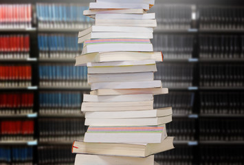 Stacking books with bookshelfs background in the library room. Education and knowledge high as a mountain concept.