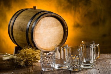 empty beer glasses on a wooden table with spikelets and a barrel