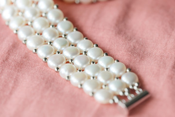 Beautiful white pearl necklace on a coral color textile background close up
