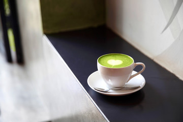 White cup of tasty matcha latte with love art.