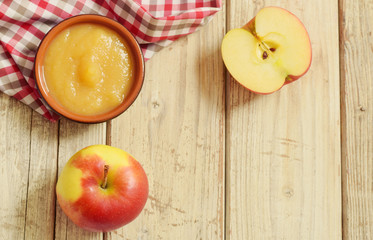 Apple puree in bowl with raw apples top view