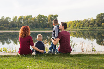 Children, parenthood and nature concept - Big family sitting on the grass