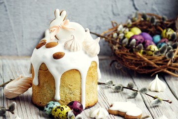 Easter cake in the form of a rabbit on a table, a table decorated with rabbits, against a background of a basket with multi-colored quail eggs, horizontal format