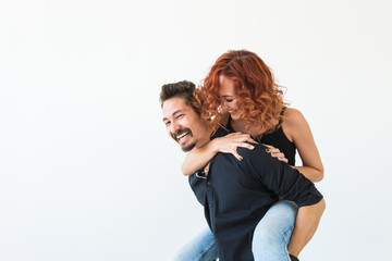 People and love concept - Beautiful pretty woman sitting at man's back and embracing him on whi