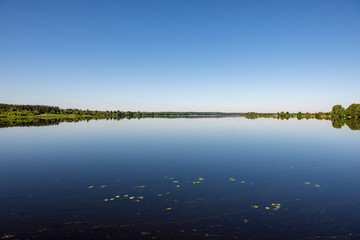reflections of shore trees in the calm water of a lake