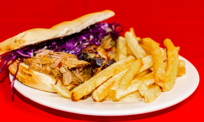 Pork cabbage sandwiches and fries. Plated with a red background.