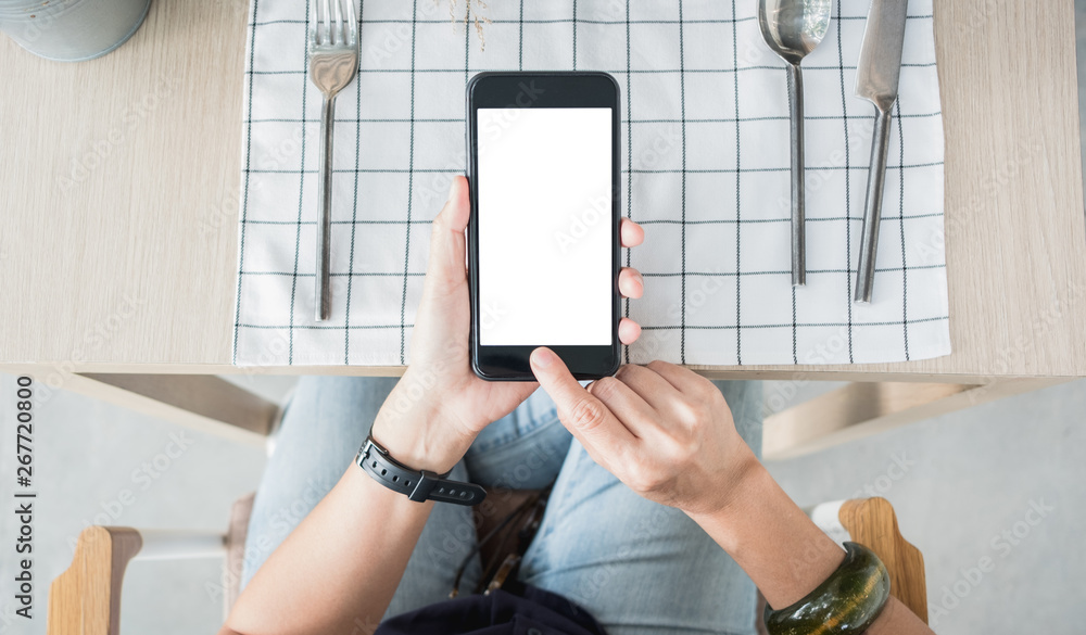 Poster hand holding mobile blank screen over restaurant table order food online.mock up screen for display 