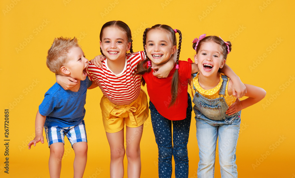 Wall mural group of cheerful happy children on colored yellow background.