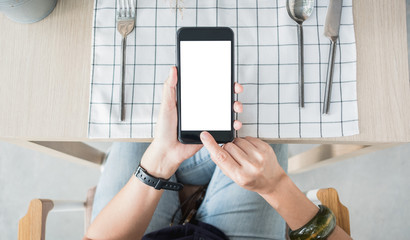 hand holding mobile blank screen over restaurant table order food online.mock up screen for display of design