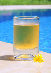  Transparent glass cup with lemonade or juice near the pool in the hot summer. Vacation. Pool. Cold drink.