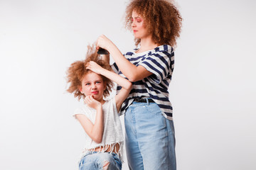 Mom combs her daughter's naughty, curly hair.