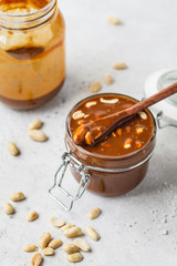 Homemade salted caramel with nuts in glass jar, copy space. Ingredient for cake snickers.