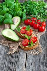 Fresh tomatoes and avocado pieces on wooden background
