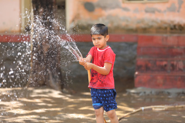 Naklejka premium indian child playing with water tube