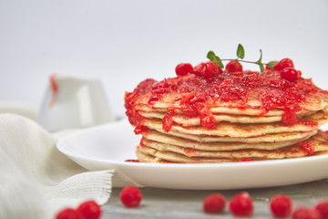 American pancake with jam - berry, viburnum, cranberry on grey background. Homemade pancakes with berry sauce and mint. Healthy breakfast with fresh hot pancakes with berry jam