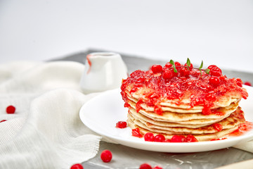 American pancake with jam - berry, viburnum, cranberry on grey background. Homemade pancakes with berry sauce and mint. Healthy breakfast with fresh hot pancakes with berry jam