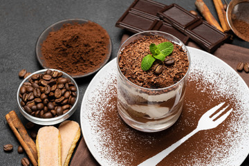 Classic tiramisu dessert in a glass on dark concrete background