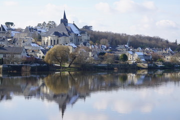 mirror reflection of an old stone church and village  on a white winter day in the Loire Valley, France