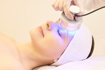 Naklejka premium Light infrared therapy. Cosmetology head procedure. Beauty woman face. Cosmetic salon device. Facial skin rejuvenation