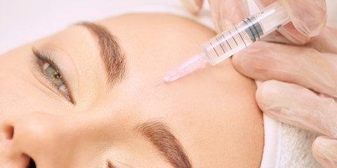 Forehead woman surgery. Anti wrinkle filler. Cosmetology injection. Face skin rejuvenation. Doctor injecting collagen acid