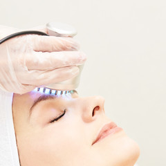 Light infrared therapy. Cosmetology head procedure. Beauty woman face. Cosmetic salon device. Facial skin rejuvenation
