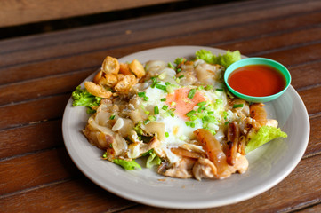 Stir-fried rice noodle with chicken, squid, fry egg and lettuce