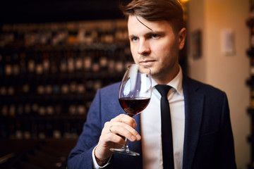 handsome awesome man enjoys drinking wine. close up photo.man has extensive knowledge of wine production and wine service