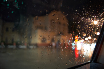 Raindrops on a window glass, night city lights at the background