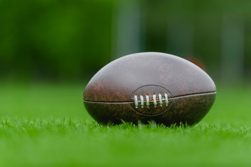 American football, rugby ball on green grass field background