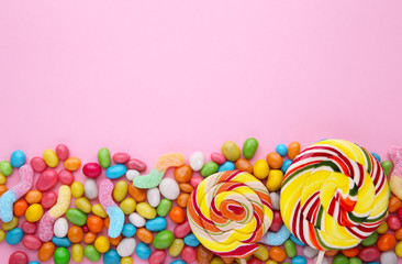 Fototapeta na wymiar Colorful lollipops and different colored round candy on pink background