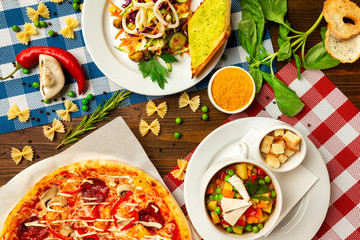 Top view image of italian style business lunch of pizza, soup and salad at wooden table background.