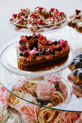 Cake in a shape of heart decorated with berries, served on a banquet table.