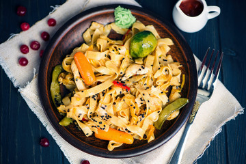 Chinese spicy noodles with vegetables on a plate with cranberry sauce