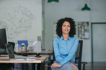 Smiling young businesswoman sitting at her desk in an office