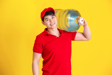 Asian delivery courier with bottle of water on color background