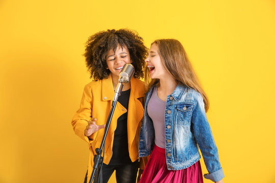 Teenage Girls With Microphone Singing Against Color Background