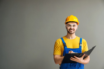 Male electrician with documents on grey background